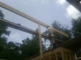 Carpenter setting a ridge beam over a new addition frame — Ice Dam Removal by Roofing Brothers in Augusta